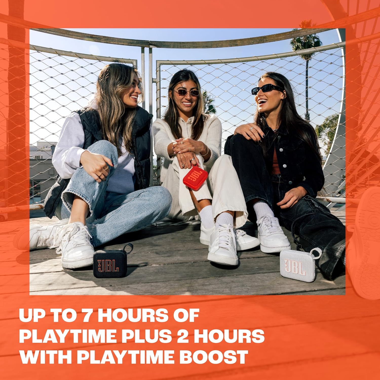 Amigas ouvindo música ao ar livre com caixas JBL Go 4, com a versão preta em destaque